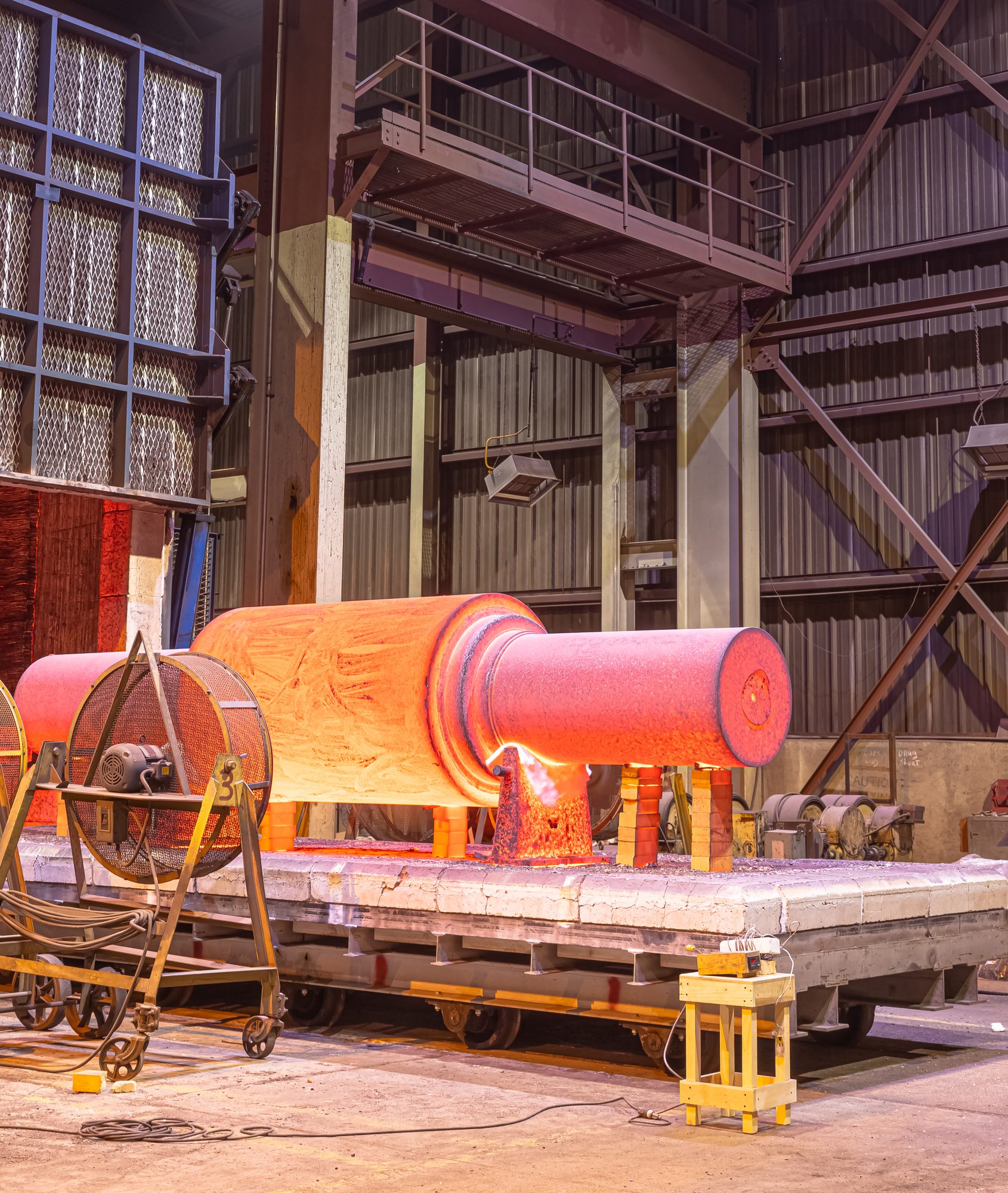 A large mill roll still glowing orange on a cooling car